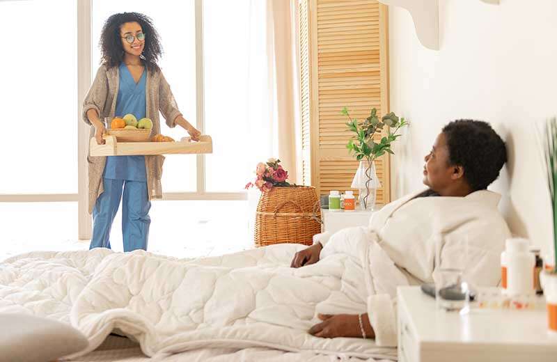 Nurse bringing tray with breakfast for patient after plastic surgery